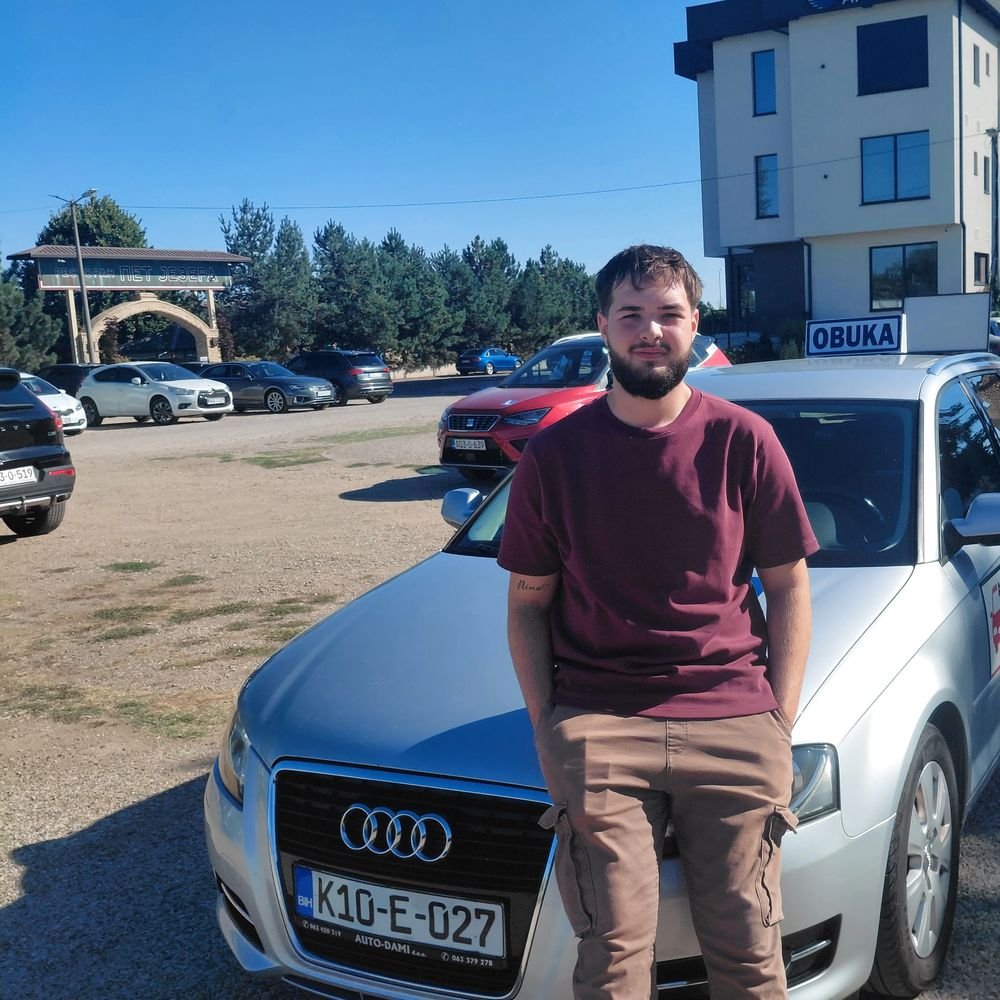 Kandidat naslonjen na automobil Autoškole Mitrović & Tea sa oznakom OBUKA